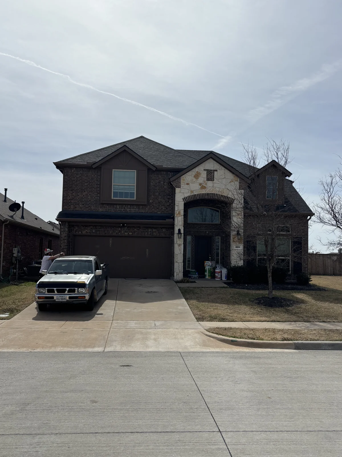 Front view of the finished Brilliant Black shingle roof on the brick and stone home in Anna, Texas.