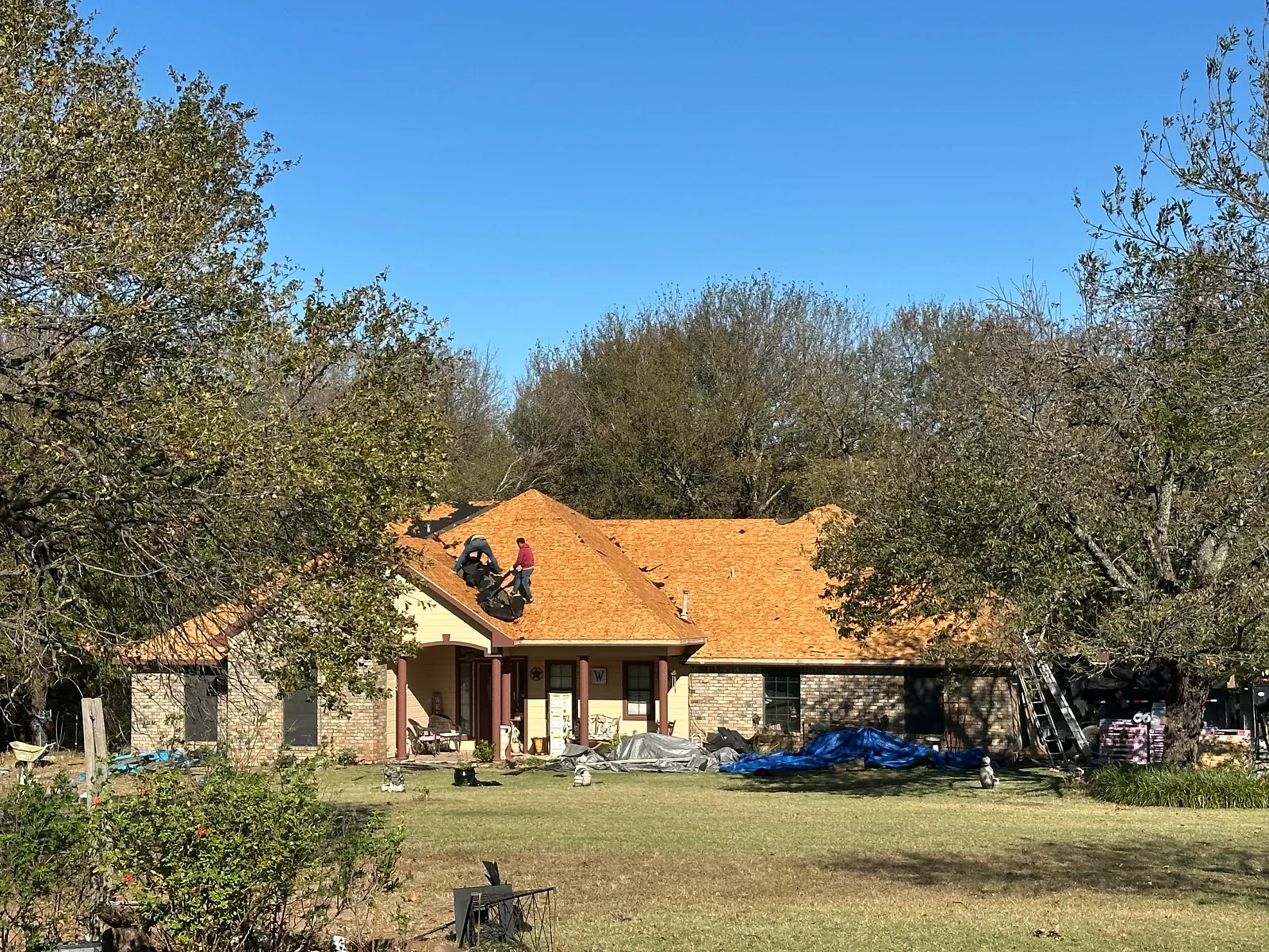 Front view of the Denison home with roof decking exposed during tear-off.