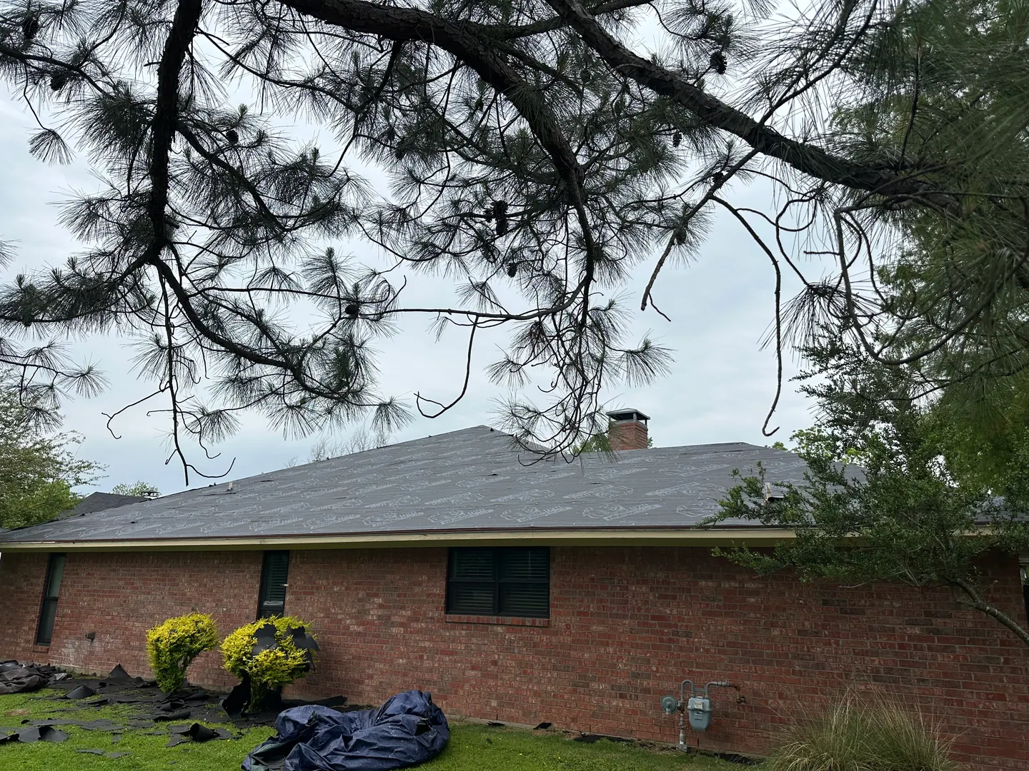 Side view of the brick home with roof underlayment in place before Teak shingle installation.