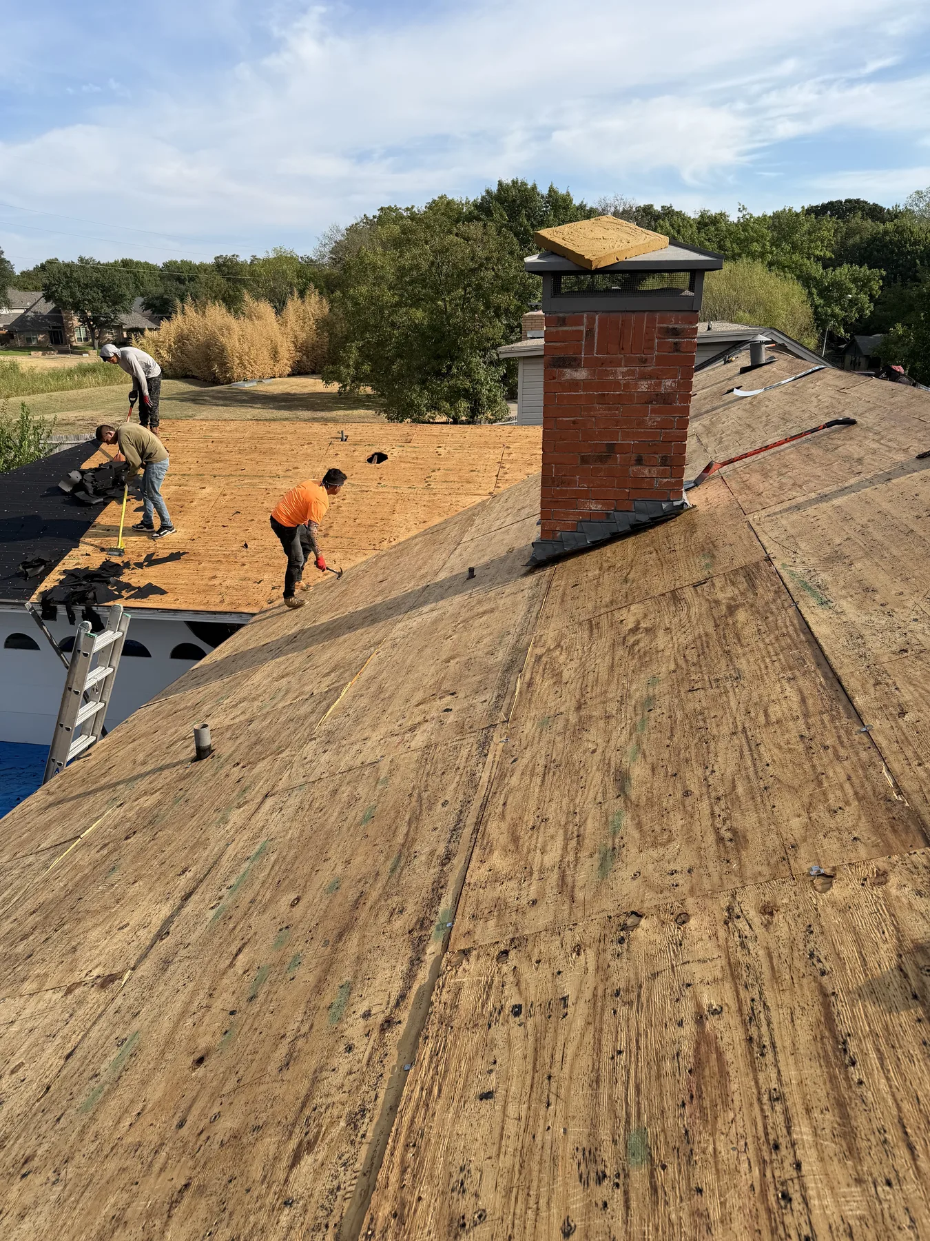 Exposed roof decking being inspected around a chimney during a Sherman Texas reroof